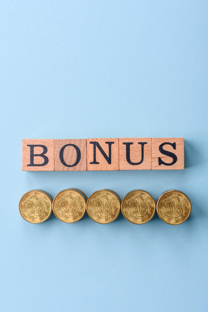 Word bonus written with wooden cubes and stacks of coins underneath all put on a plain surface